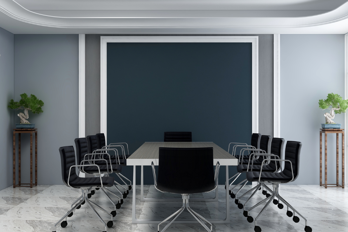A modern conference room with a striking contrast of light gray walls and a bold dark blue accent wall, complemented by sleek black chairs and minimal decor. The neutral tones create a professional yet inviting atmosphere.
