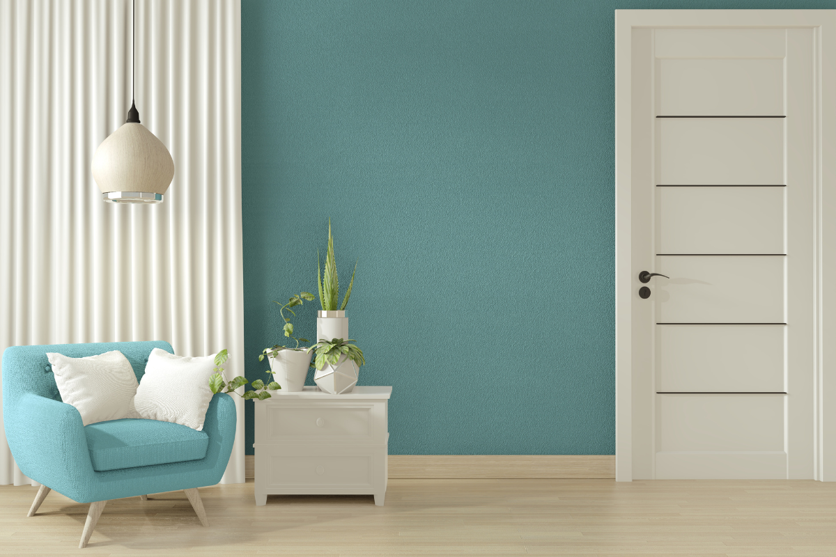 Cozy living space with teal accent wall, light wood flooring, and a turquoise armchair paired with white accents and potted plants.